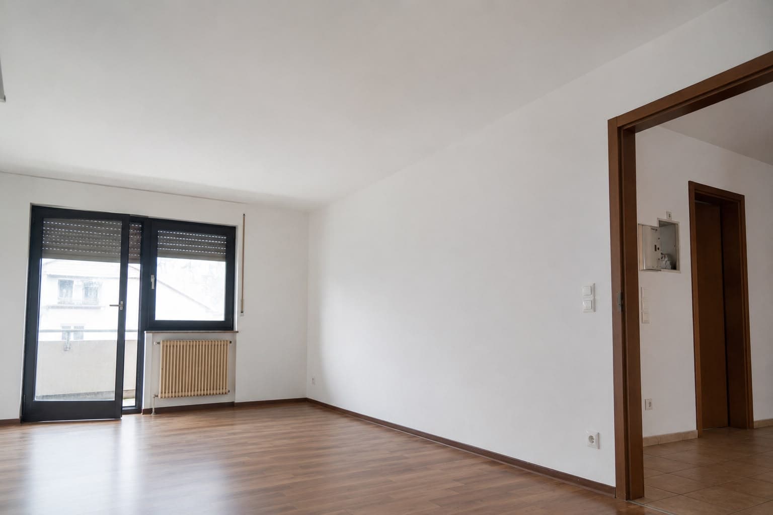 Derselbe Wohnraum nach der Sanierung: trockene, frisch gestrichene Wände und Decke sowie neu verlegter Holzboden